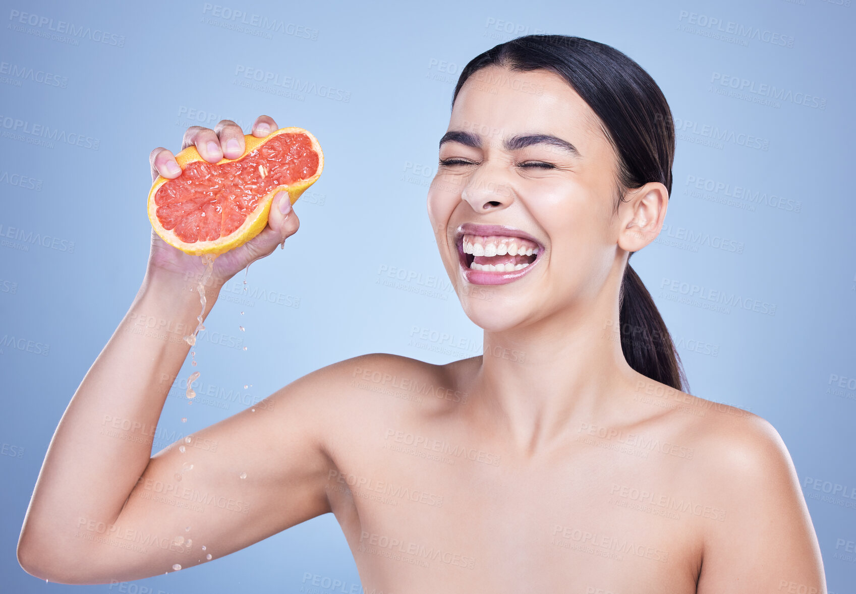Buy stock photo A  happy mixed race woman holding a grapefruit. Hispanic model promoting the skin benefits of citrus diet against a blue copyspace background