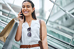 Trendy young woman talking on a cellphone while out on a shopping spree. Female enjoying retail therapy while staying connected with her smartphone. Calling to find a sale and discount. Planning to spend money