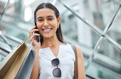 Portrait of a woman smiling while staying connected with a cellphone while out shopping. Trendy female on a call telling friends about a sale or discount at a mall. Enjoying the weekend with retail therapy.