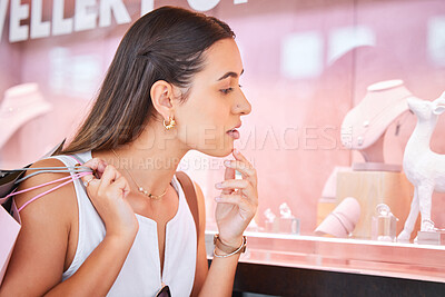 Young woman looking at jewellery on display through a window during a shopping spree in a mall. One female only doing window shopping. Shopaholic holding bags and deciding whether to buy accessories