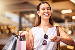 Portrait of a young mixed race woman during a shopping spree in a mall. One hispanic female only enjoying retail therapy. Shopaholic holding bags smiling and looking happy while checking time on watch in a mall