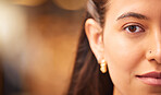Close up portrait of a beautiful young womans face with smooth flawless skin. Indian female showing off her natural beauty and clear complexion while posing with a nose piercing, half faced