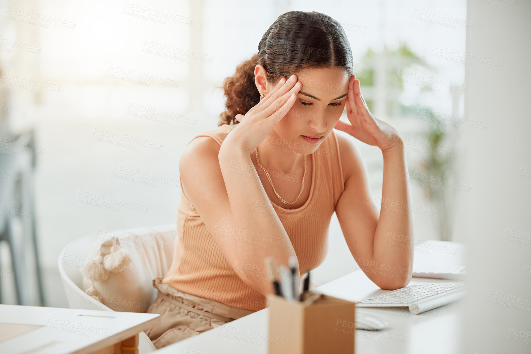 Buy stock photo One anxious young hispanic business woman suffering with a headache while working on a computer in an office. Entrepreneur feeling overworked, tired and anxious about deadlines. Mentally frustrated with burnout and stress