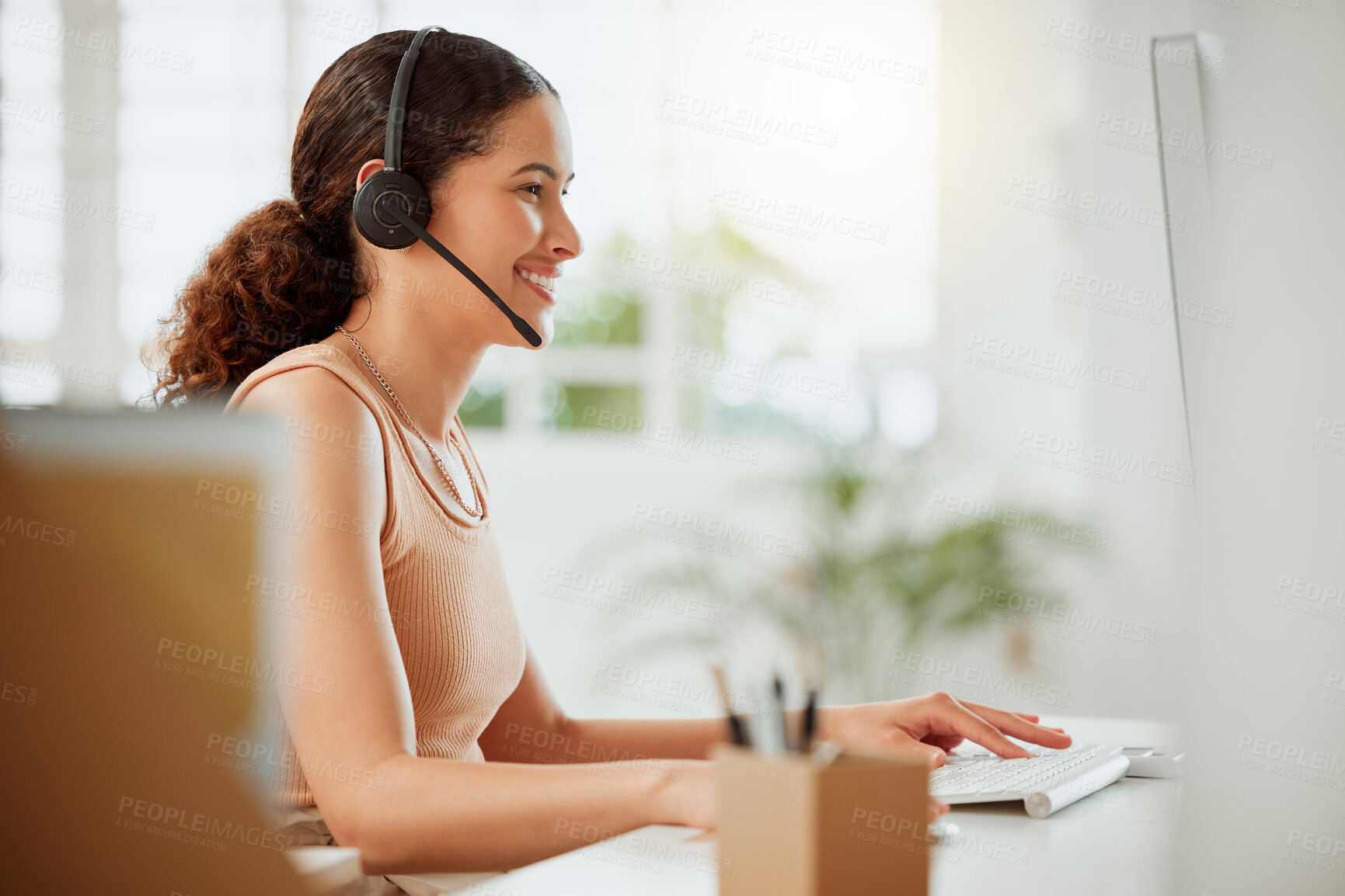 Buy stock photo One happy young hispanic female call centre telemarketing agent talking on a headset while working on a computer in an office. Confident and friendly mixed race business woman consultant operating helpdesk for customer service support