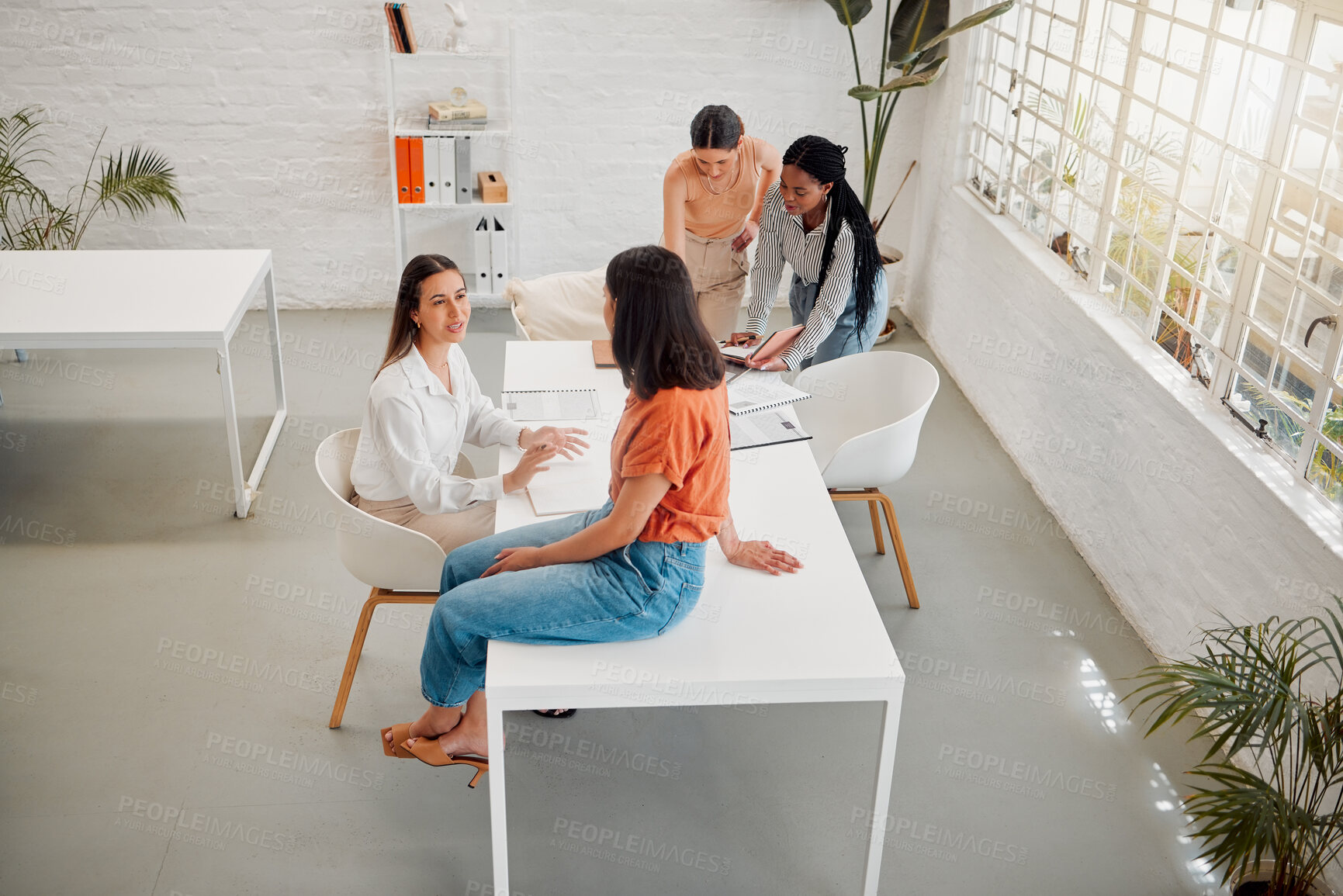 Buy stock photo Diverse group of business women from above discussing plans while working together around a table in an office. Overhead of colleagues in workspace room in a creative startup agency