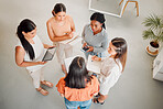 Diverse group of five businesswomen having a meeting together in at work. Serious businesspeople talking and planning while standing in an office from above