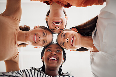 Buy stock photo Four happy businesswomen joining their heads together in a circle in an office at work. Diverse group of cheerful businesspeople having fun standing with their heads together in unity
