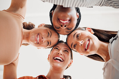 Buy stock photo Group of happy businesswomen joining their heads together in a circle in an office at work. Diverse group of joyful businesspeople having fun standing with their heads together in support