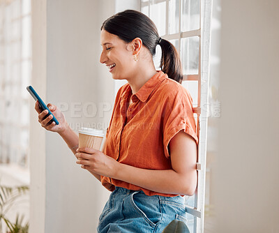 Buy stock photo Young happy mixed race businesswoman using her phone while drinking a coffee alone in an office at work. One joyful hispanic businessperson laughing while using social media on her cellphone and holding a coffee cup on a break standing at work