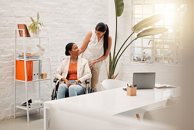 Buy stock photo Young happy mixed race businesswoman helping a colleague in a wheelchair to her office at work. Content hispanic businessperson with a disability being helped to her desk at work