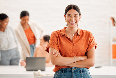 Young happy mixed race businesswoman standing with her arms crossed in an office at work. Confident cheerful hispanic businessperson standing in a meeting at work