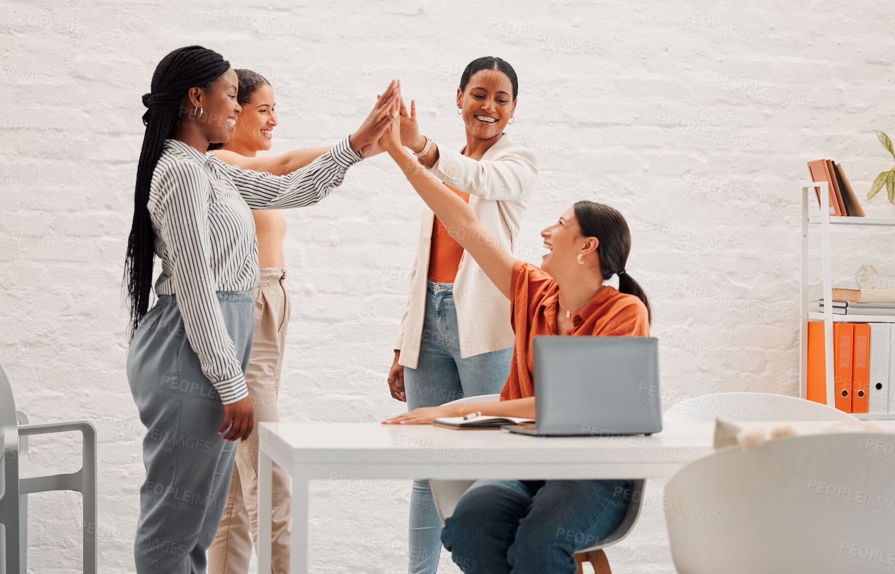Buy stock photo Four happy businesswomen joining their hand together in an office at work. Diverse group of cheerful businesspeople giving each other a high five for support