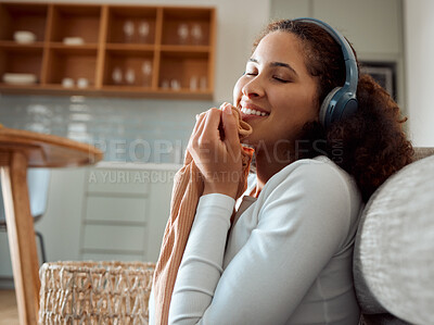 Buy stock photo Woman enjoying the feel of a soft top. Young woman listening to music, cleaning laundry. Mixed race woman holding fresh, washed clothing. Happy woman rubbing clean clothing on her face