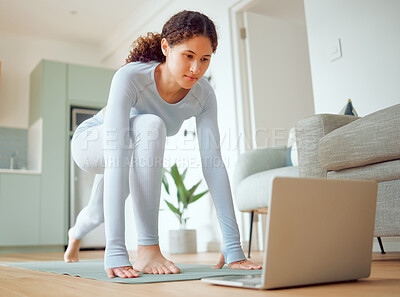 Buy stock photo Beautiful young mixed race woman using a laptop to follow an online class while practicing yoga at home. Hispanic female exercising her body and mind, finding inner peace, balance and clarity