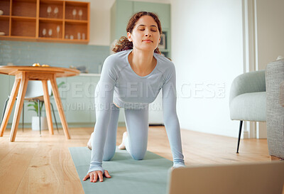 Beautiful young mixed race woman using a laptop to follow an online class while practicing yoga at home. Hispanic female exercising her body and mind, finding inner peace, balance and clarity