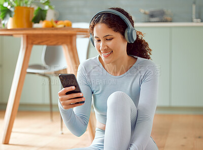 Beautiful young mixed race woman listening to music while taking a break from practicing yoga at home. Hispanic female using her phone to text message, online chat or browse social media while resting