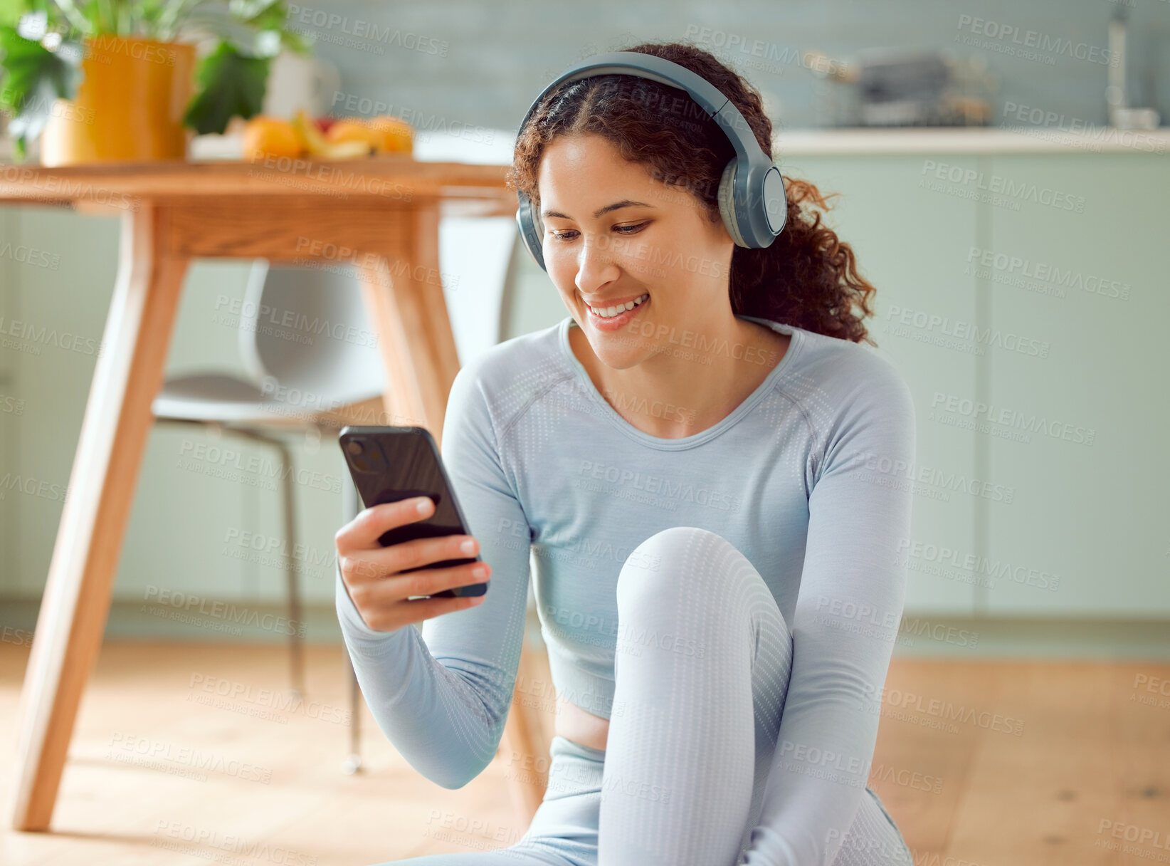 Buy stock photo Beautiful young mixed race woman listening to music while taking a break from practicing yoga at home. Hispanic female using her phone to text message, online chat or browse social media while resting