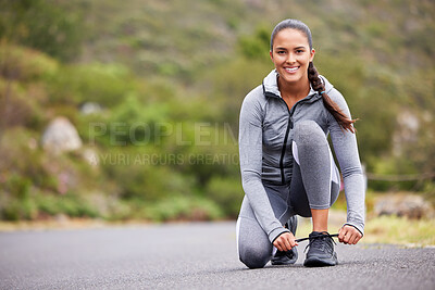 Buy stock photo Active and fit woman tying the laces of her sneakers for exercise outdoors. Athlete fixing her shoes to get ready for a run or jog in the morning. Preparing for a refreshing cardio workout outside