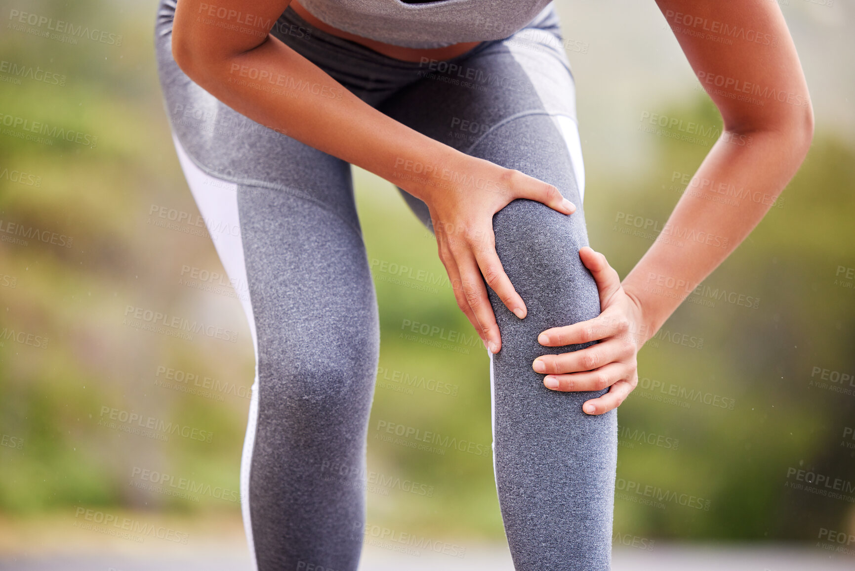 Buy stock photo Active woman holding her leg in pain while exercising outdoors. Closeup of an athlete suffering with a painful knee injury, causing discomfort and strain.  Muscle sprain from a fractured joint