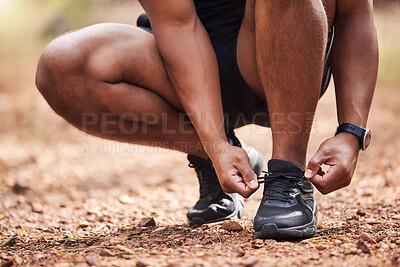 Unknown mixed race man crouching down to tie his shoelaces before his daily outdoor workout. Athletic and fit indian runner getting ready for exercise. Routine sports and physical activity is healthy