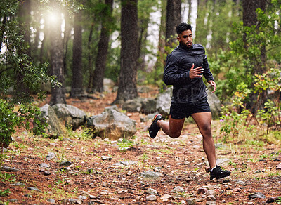 Athletic man running in a park. Muscular male training outside. Jogger starting his morning with some cardio exercises. Sporty mixed race athlete keeping fit in a forest while training for a marathon