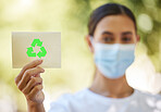 One unknown mixed race woman holding a paper with recycling sign for environment conservation and protection. Hispanic woman wearing face mask promoting go green. Blurred woman holding recycle symbol