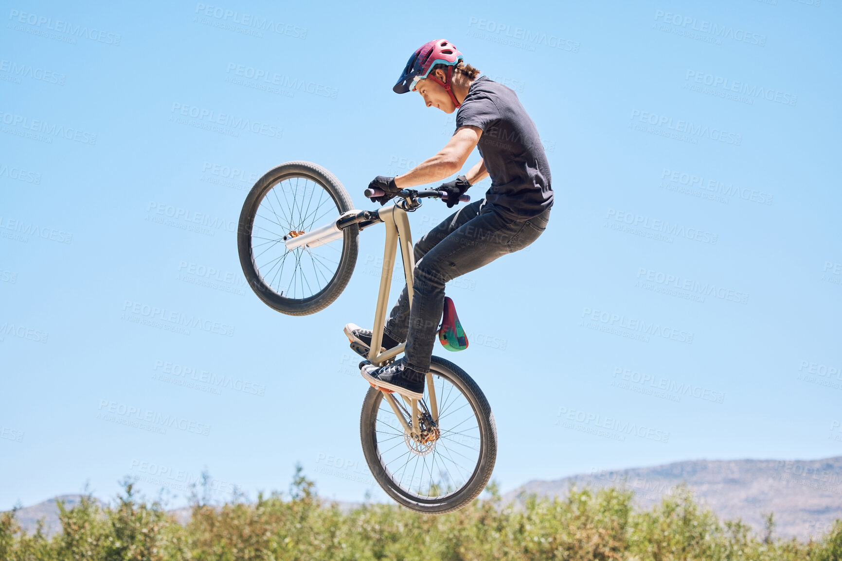 Buy stock photo Young man showing his cycling skills while out cycling on a bicycle outside. Adrenaline junkie practicing a dirt jump outdoors. Male wearing a helmet doing tricks with a bike. Passionate and energetic