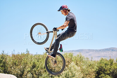 Buy stock photo Man showing cycling skills while out cycling on a bicycle outside. Adrenaline junkie practicing a dirt jump outdoors. Male wearing a helmet doing tricks with a bike. Having fun doing extreme sports