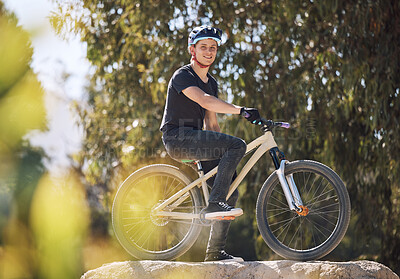 Buy stock photo Portrait of a handsome man wearing a helmet and taking a break from cycling on his bicycle outside. Male athlete exercising in a park. Sporty male training on his bike. Keeping his heart healthy