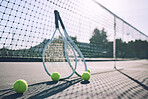 Group of tennis balls and rackets against a net on an empty court in a sports club during the day. Playing tennis is exercise, promotes health, wellness and fitness. Gear and equipment after a game