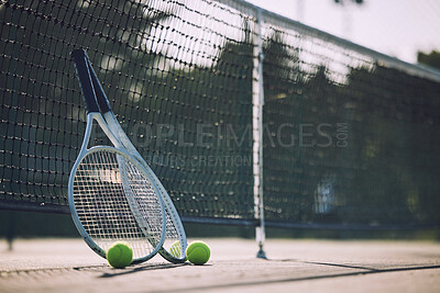 Buy stock photo Group of tennis balls and rackets against a net on an empty court in a sports club during the day. Playing tennis is exercise, promotes health, wellness and fitness. Gear and equipment after a game