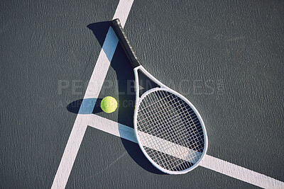 Tennis racquet and ball on an empty sports court outside from above on a sunny day. Sports gear and equipment for leisure or a professional player. A hobby that promotes exercise, fitness and wellness