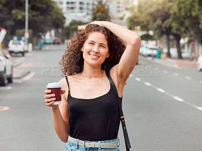 Buy stock photo One happy beautiful young mixed race woman exploring the city while holding a takeaway coffee and touching her curly brunette hair. Hispanic travelling woman enjoying the view downtown on the weekend