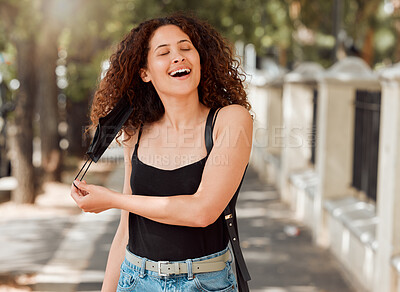 Buy stock photo Beautiful young mixed race woman with an afro removing her mask and looking happy. The end of the corona virus pandemic. female looking free and relieved while breathing fresh air outside in the city 