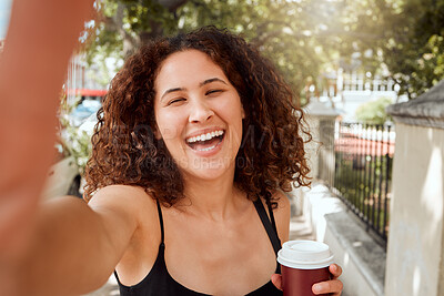Buy stock photo Mixed race young woman taking a selfie while out exploring the city. Portrait of a smiling tourist holding a coffee and taking a photo while enjoying her weekend downtown. 
