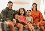 Portrait of a mixed race family of five relaxing on the sofa at home. Loving black family being affectionate on the sofa. Young couple bonding with their adopted kids at home