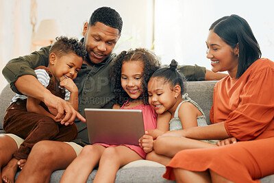 A happy mixed race family of five relaxing on the sofa at home. Loving black family being affectionate on the sofa while using a digital tablet and streaming. Young couple bonding with their kids and watching movies at home