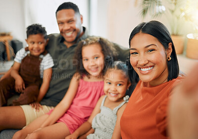 Portrait of a mixed race family of five relaxing on the sofa at home. Loving black family taking a selfie on the sofa. Young couple bonding with their adopted kids at home