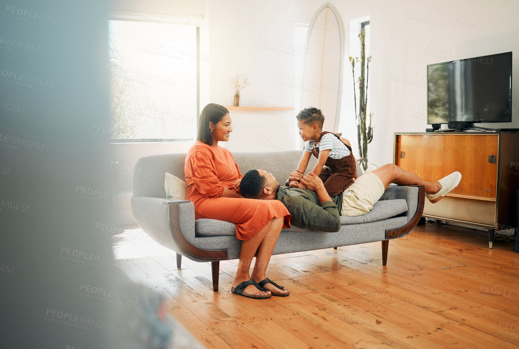Buy stock photo A happy mixed race family of three relaxing in the lounge and being playful together. Loving black family bonding with their son while playing fun games on the sofa at home