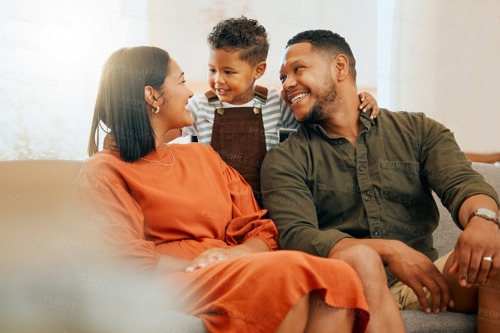 Buy stock photo A happy mixed race family of three relaxing in the lounge  together. Loving black family bonding with their son while talking on the sofa at home