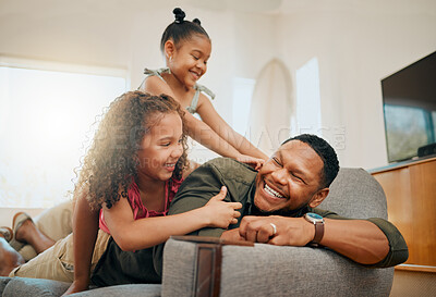 A happy mixed race family of three relaxing in the lounge and being playful together. Loving black single parent bonding with his daughters while playing fun games on the sofa at home