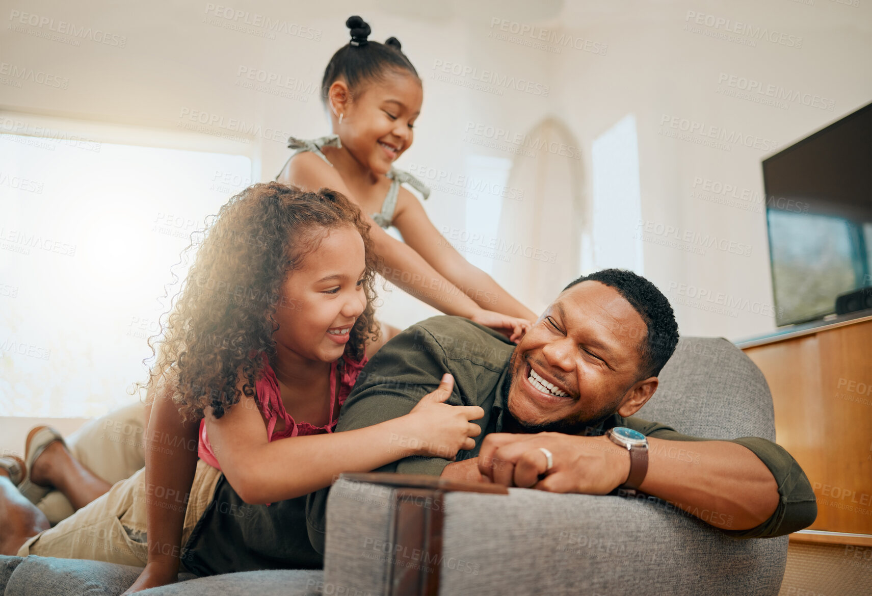 Buy stock photo A happy mixed race family of three relaxing in the lounge and being playful together. Loving black  single parent bonding with his daughters while playing fun games on the sofa at home