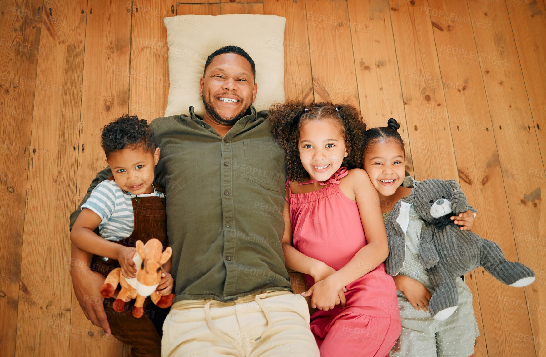 Buy stock photo A happy mixed race family of four relaxing and lying on the lounge floor together. Loving black single parent bonding with his kids while being affectionate at home