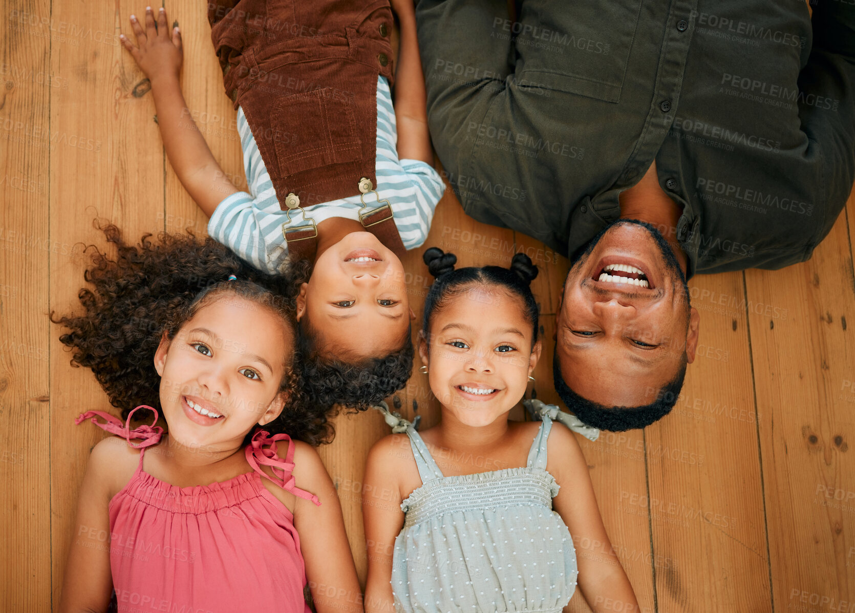 Buy stock photo A happy mixed race family of four relaxing and lying on the lounge floor together. Loving black single parent bonding with his kids while being affectionate at home