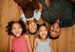 A happy mixed race family of four relaxing and lying on the lounge floor together. Loving black single parent bonding with his kids while being affectionate at home