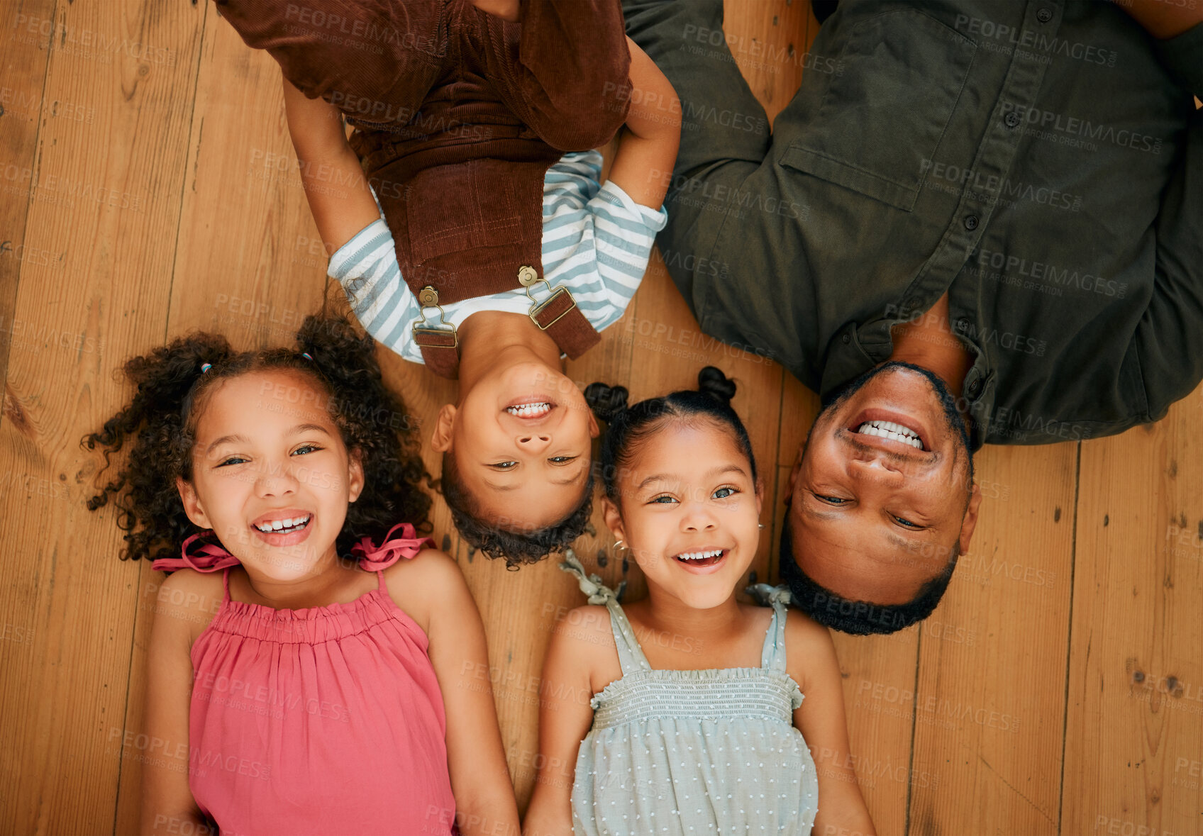 Buy stock photo A happy mixed race family of four relaxing and lying on the lounge floor together. Loving black single parent bonding with his kids while being affectionate at home