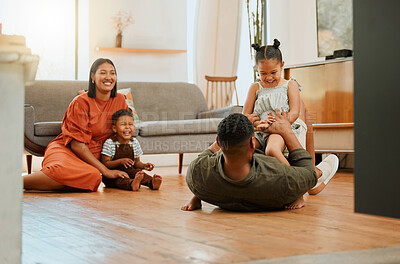 A happy mixed race family of four relaxing in the lounge and being playful together. Loving black family bonding with their kids while playing fun games on the floor at home