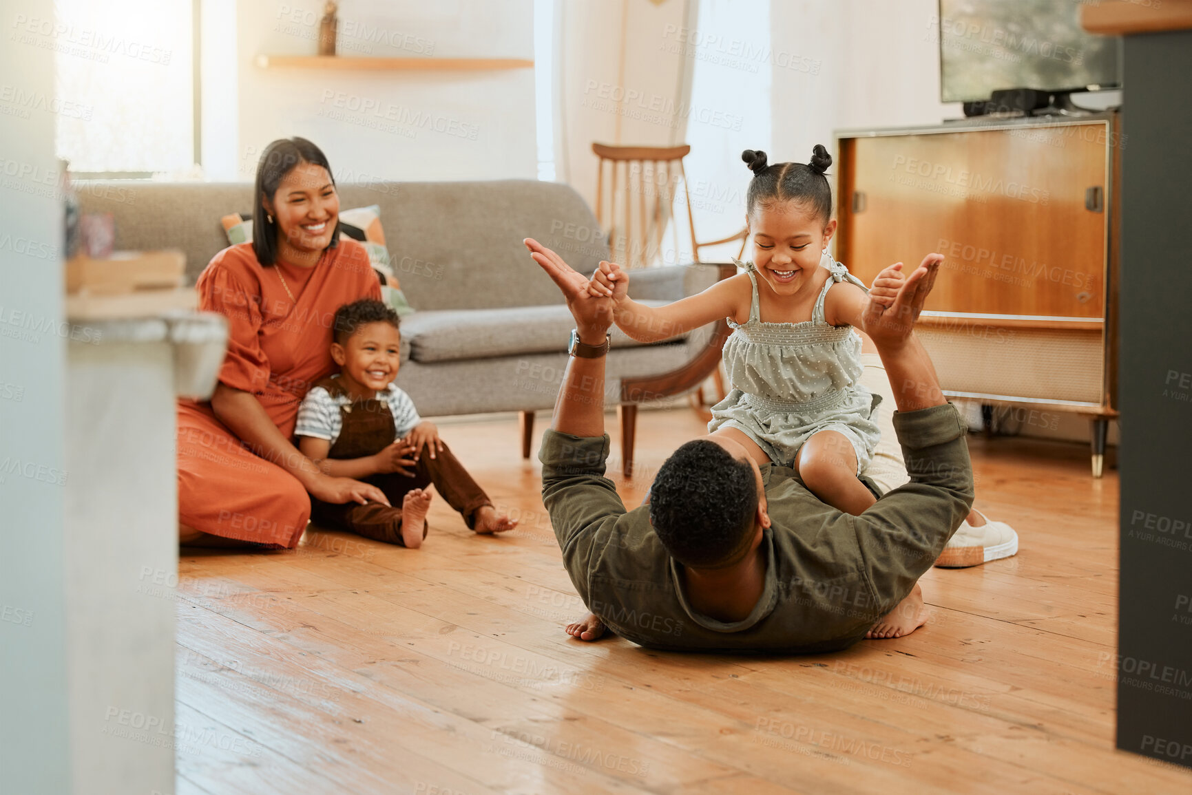 Buy stock photo A happy mixed race family of four relaxing in the lounge and being playful together. Loving black family bonding with their kids while playing fun games on the floor at home