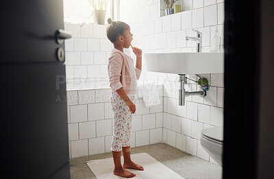 Buy stock photo One mixed race adorable little girl brushing her teeth in a bathroom at home. A happy Hispanic child with healthy daily habits to prevent cavities and strengthen enamel