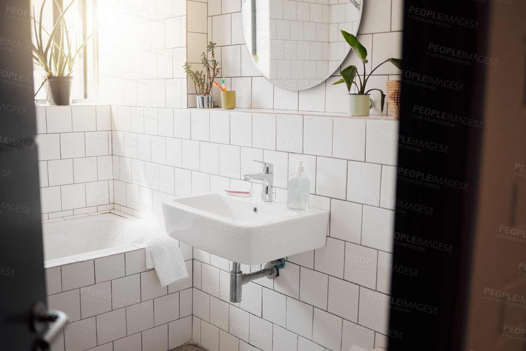 Buy stock photo A clean and tidy bathroom inside a house. A basin, bath, with ceramic tiling and a round mirror hanging on the wall. A clean, hygienic, bright room